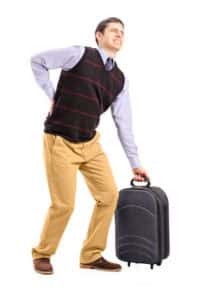 גבר עם מזוודה כבדה סובל מכאב גב תחתון